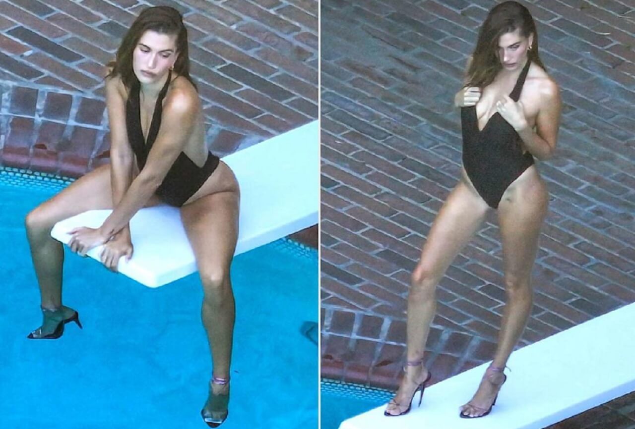 Hailey Bieber poses in a black swimsuit on a diving board for GQ’s Men of the Year cover shoot.