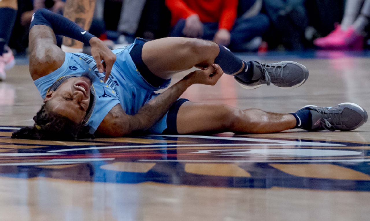 Ja Morant sitting courtside in Memphis gear after suffering a calf strain injury.