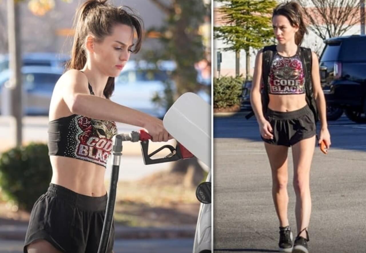 Jordon Hudson wearing Code Black cheer uniform, displaying athletic physique at a gas station.