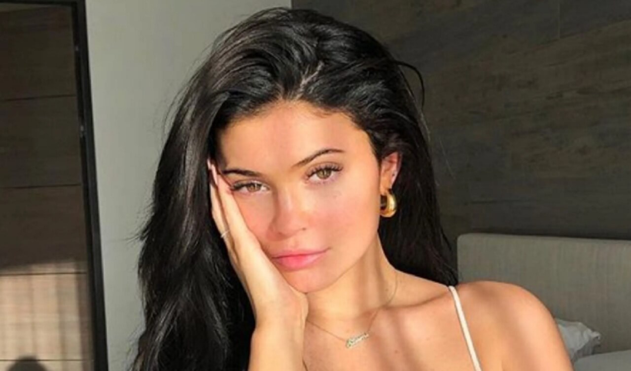 Kylie Jenner posing wrapped in a white blanket, holding a pink rose in her viral Instagram photo.