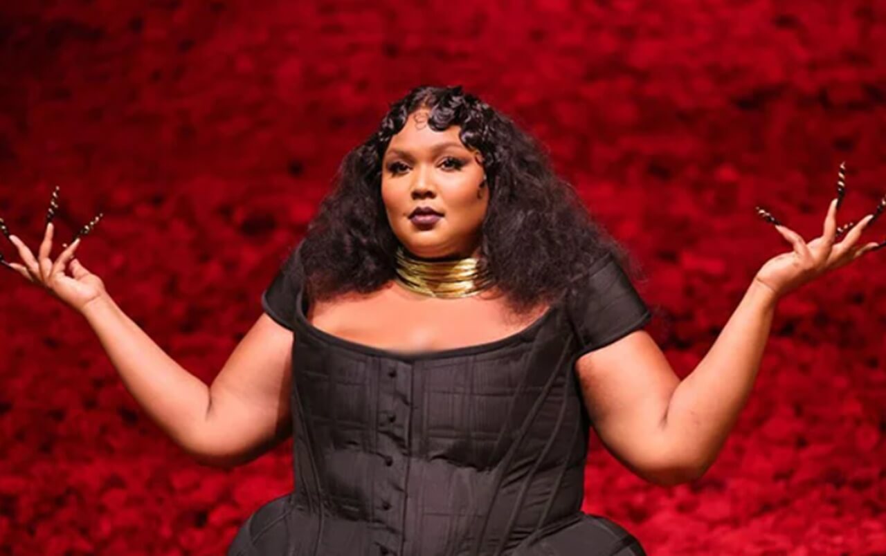 Lizzo onstage in a reflective moment during a live performance.