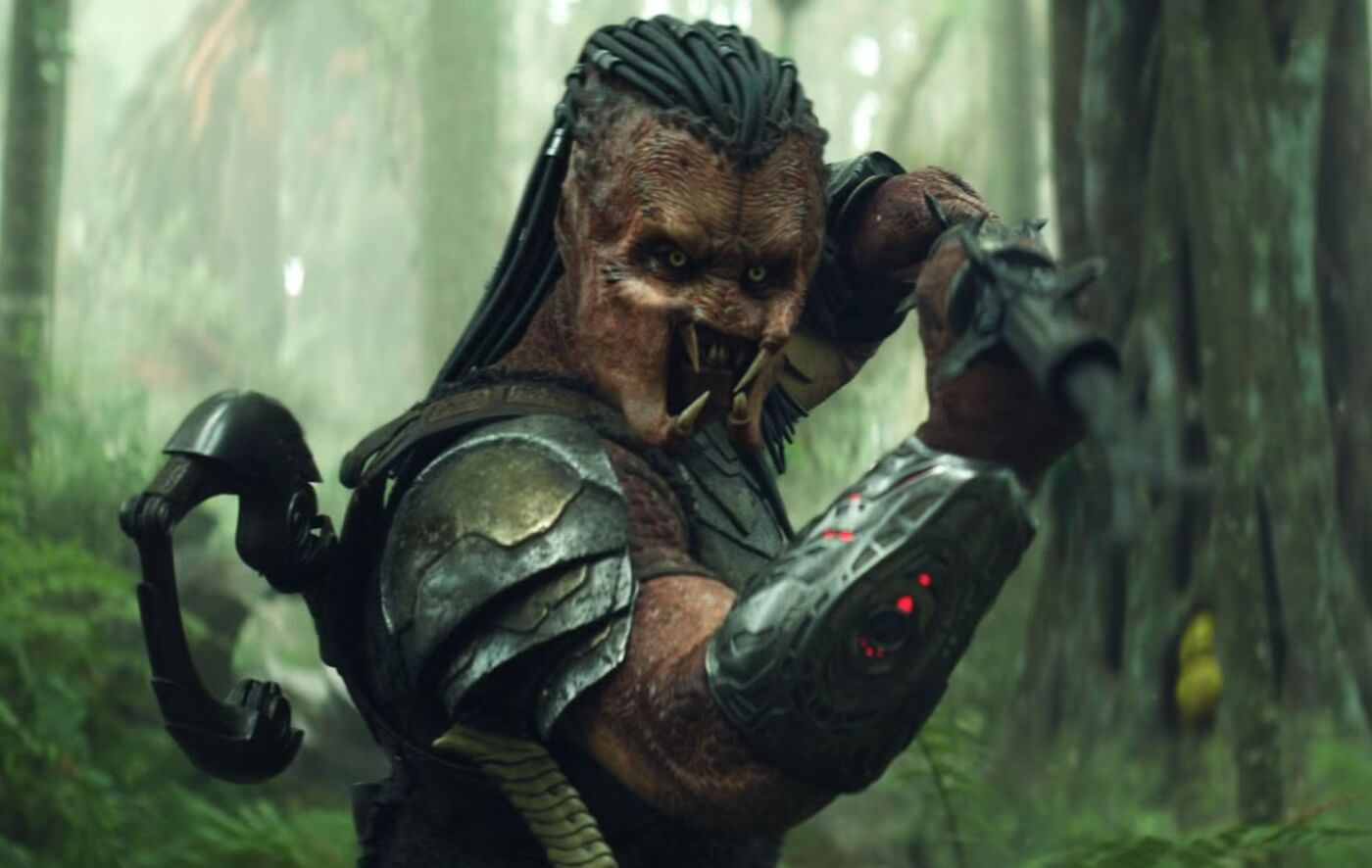 Dek stands with sword in front of explosion in Predator: Badlands.