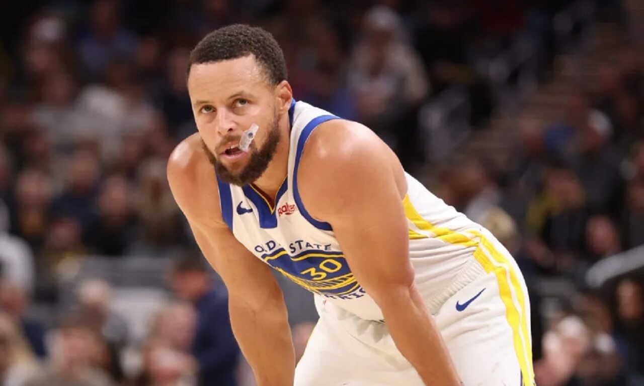 Stephen Curry watches from the bench during Warriors vs Nuggets game.