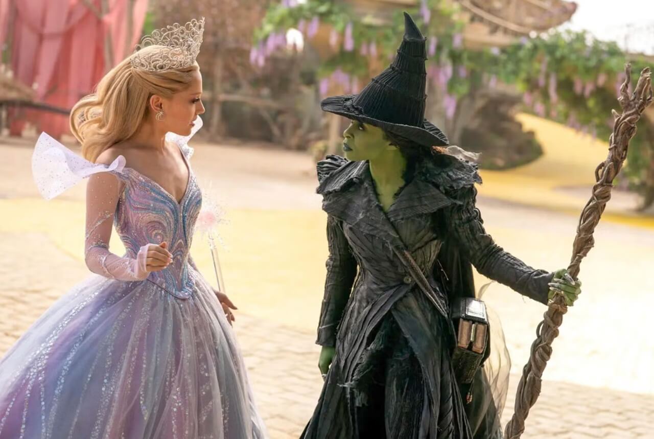 Elphaba and Glinda stand opposite each other in a tense moment from Wicked: For Good, highlighting the film’s darker tone.