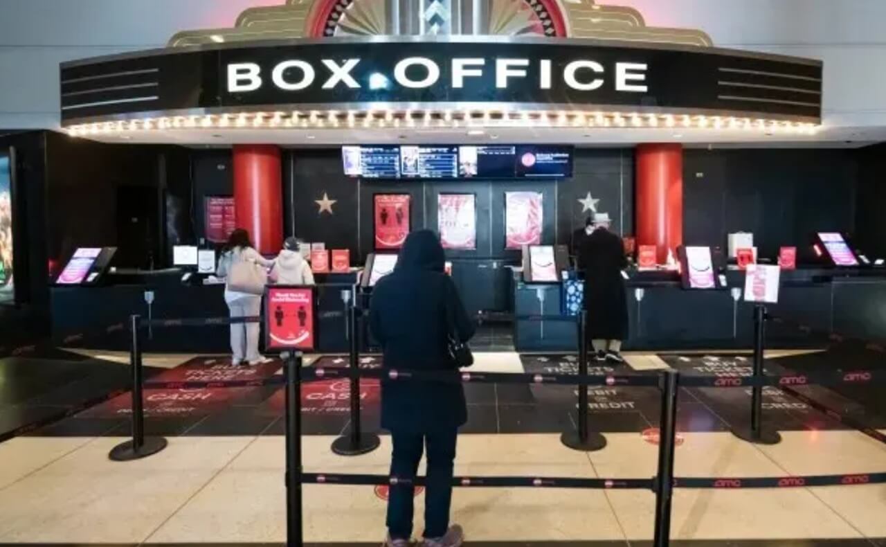 Movie theater audience watching screen showing rising global box office forecast.