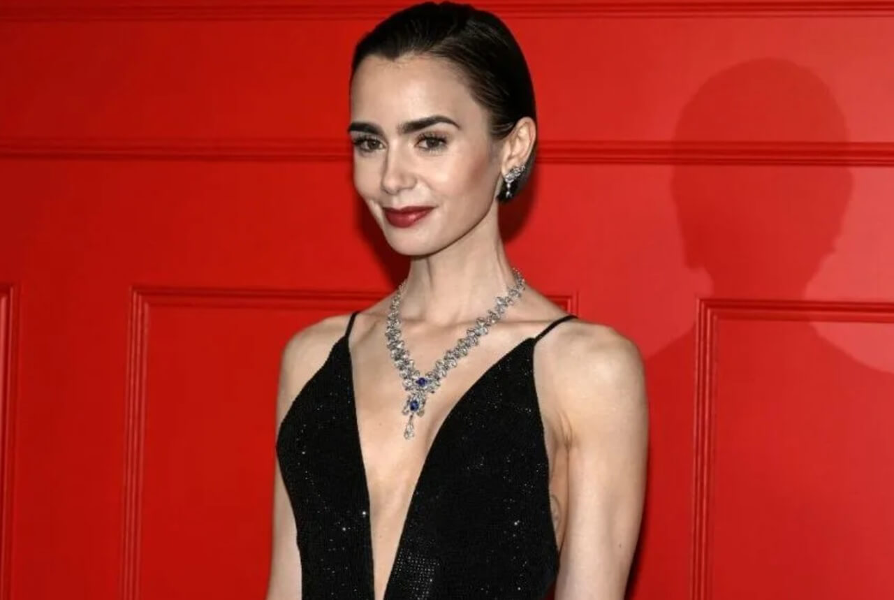 Lily Collins holding baby Tove on set of Emily in Paris beside Ashley Park.