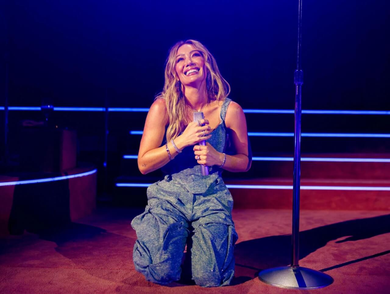 Hilary Duff on stage in Los Angeles teasing world tour with fans wearing “World Tour Loading” shirts.