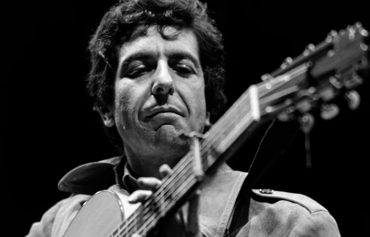 Leonard Cohen in 1967 with guitar, reflecting on his debut album.