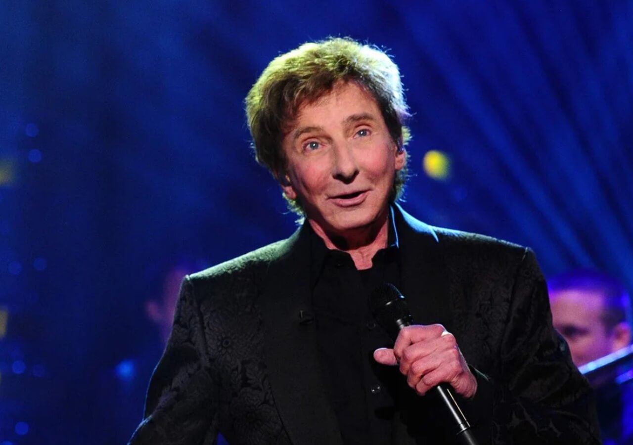 Barry Manilow performing live on stage under spotlight