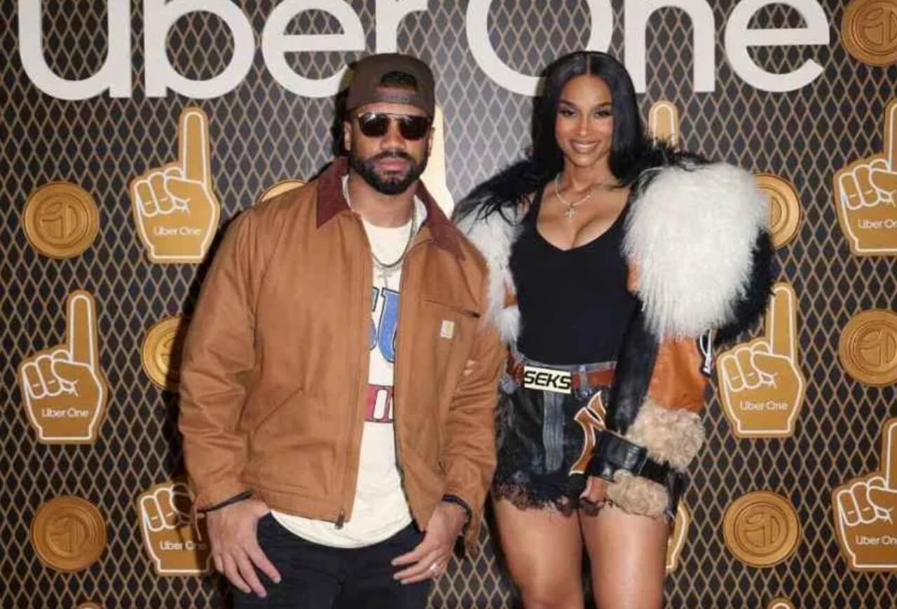 Ciara in leather miniskirt posing at Uber One party with Russell Wilson watching.