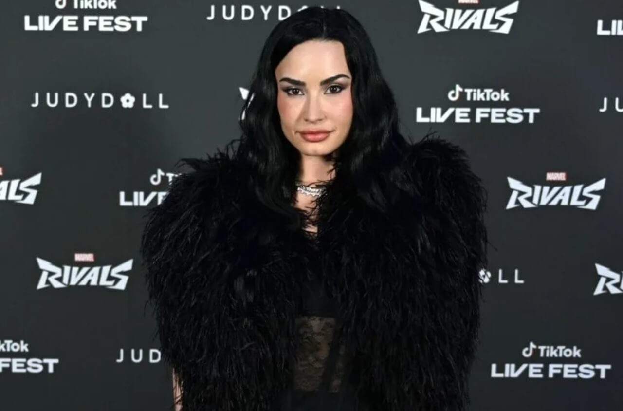 Demi Lovato enjoys a party with friends, holding a drink and smiling.