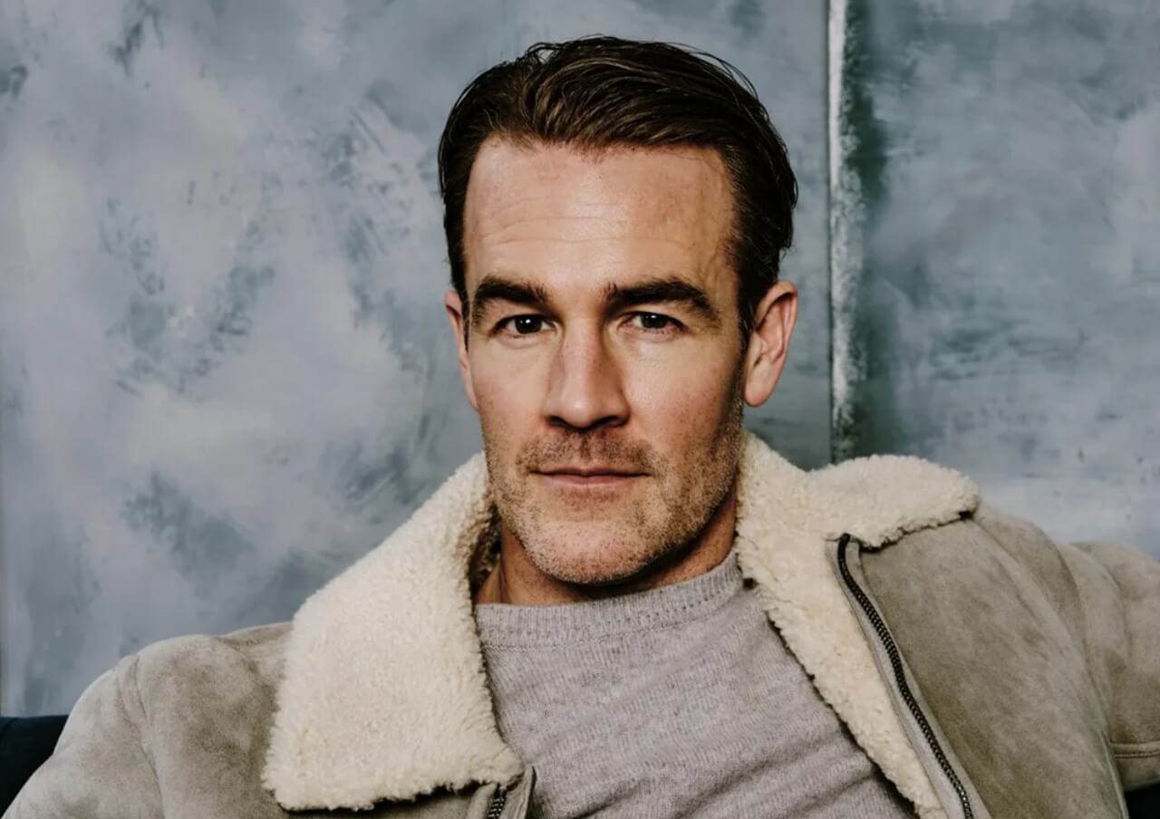 James Van Der Beek at a red-carpet event, smiling warmly in a tailored suit.
