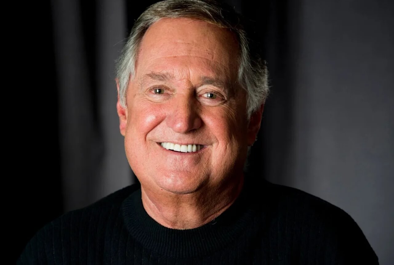 Neil Sedaka plays piano, smiling during a performance.