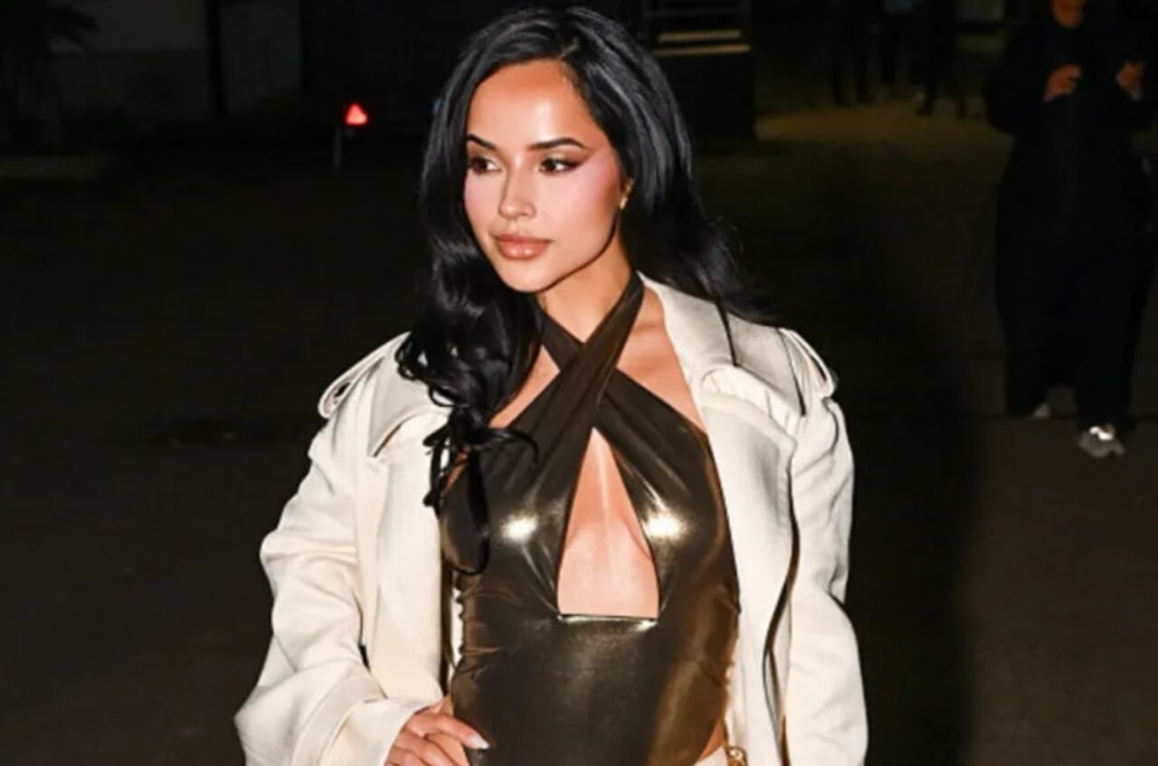 Becky G in zebra print coat with sunglasses and boots posing inside a car.