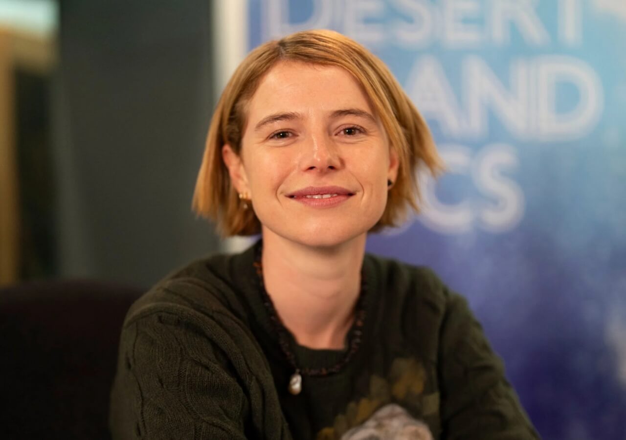 Jessie Buckley attends a film premiere, smiling on the red carpet.