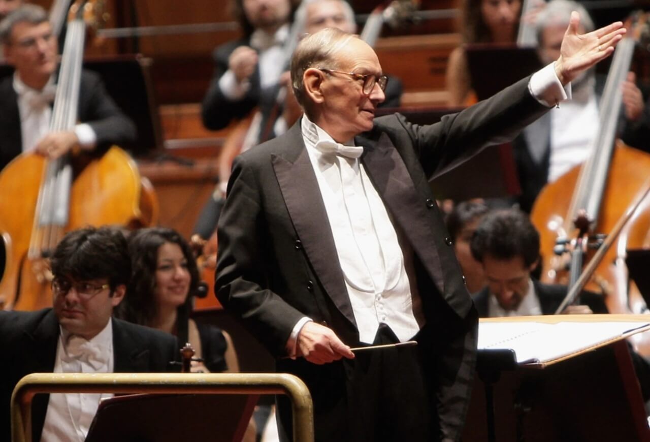 Ennio Morricone conducting an orchestra during a live concert performance.